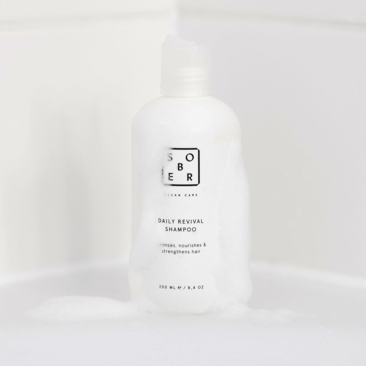 Daily Revival Shampoo neben einem Glas Wasser