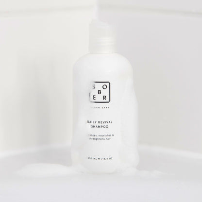 Daily Revival Shampoo neben einem Glas Wasser